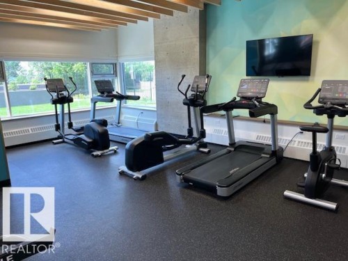 Fitness center featuring resilient flooring, full-height windows, a mounted television, and slatted wood ceiling details - 1101 10011 123 Street, Edmonton, AB 