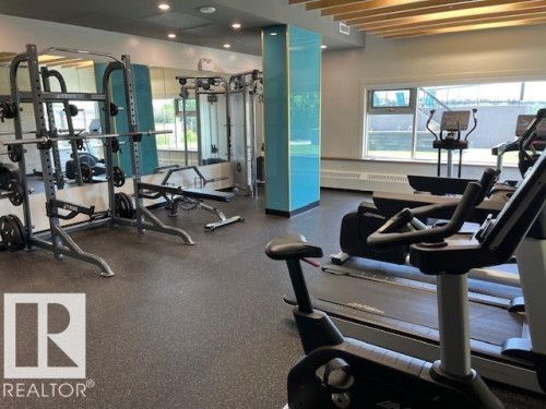 Fitness area featuring rubber flooring, a mirrored wall, and large windows - 1101 10011 123 Street, Edmonton, AB 
