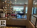 Multi-tiered chandelier illuminating a spacious common area featuring a grand piano, large windows, and a terrazzo-patterned floor - 1101 10011 123 Street, Edmonton, AB 