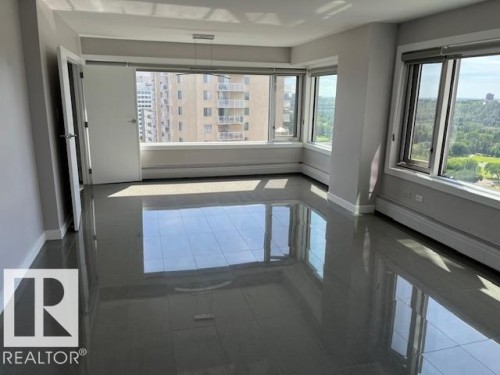 Expansive room featuring multiple large windows, dark grey tile flooring, white baseboards, and light grey walls - 1101 10011 123 Street, Edmonton, AB 