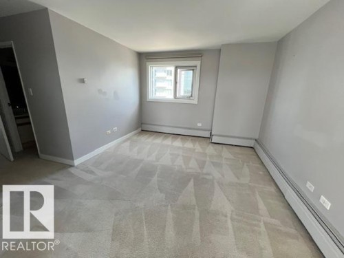 Light gray wall paint, off-white carpeting, and baseboard heating define this interior space - 1101 10011 123 Street, Edmonton, AB 