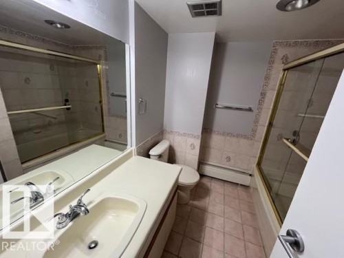 Bathroom featuring a single vanity with an integrated sink, polished chrome faucet, and a wall-mounted mirror - 1101 10011 123 Street, Edmonton, AB 