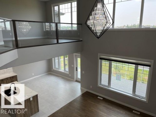 Grand two-story foyer featuring an oversized crystal chandelier, an open-concept layout, and a glass panel railing - 3810 46 Avenue, Beaumont, AB 