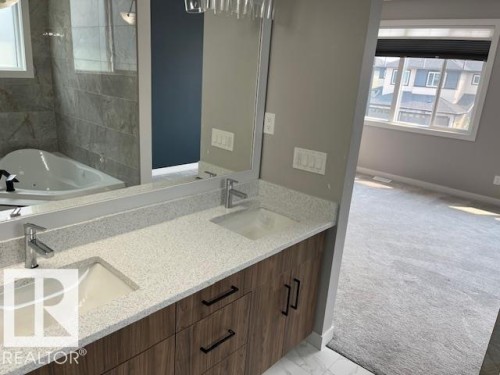 Double vanity with wood-finish cabinetry, light speckled countertops, and undermount sinks - 3810 46 Avenue, Beaumont, AB 