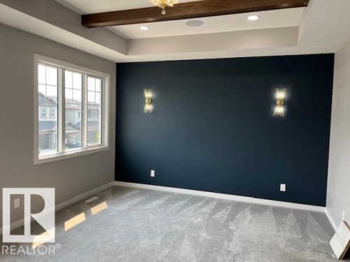 Recessed ceiling lighting, a decorative ceiling beam, and a large window with grid panes characterize this room - 3810 46 Avenue, Beaumont, AB 