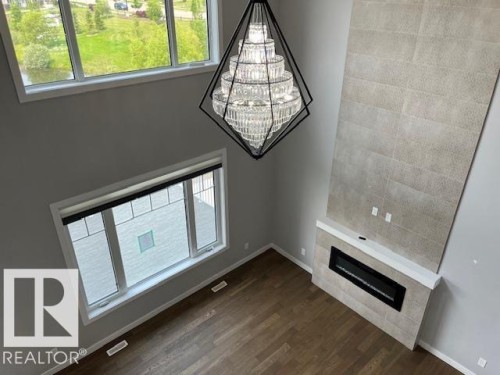 Spacious interior featuring a multi-story fireplace with light-toned tile surround and a linear electric insert - 3810 46 Avenue, Beaumont, AB 