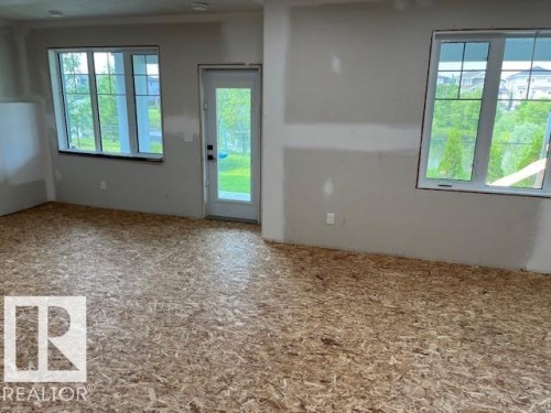 Room featuring large windows, a glass-paned door, and subflooring - 3810 46 Avenue, Beaumont, AB 
