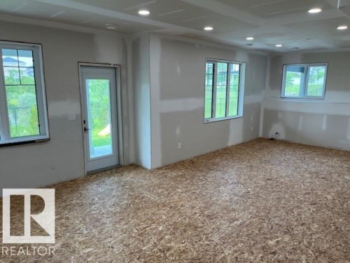 Interior room with multiple windows, recessed lighting, and a glass-paneled exterior door - 3810 46 Avenue, Beaumont, AB 