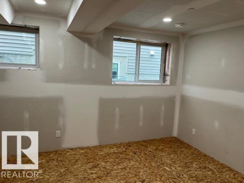 Unfinished interior space featuring recessed lighting, two windows, and exposed subflooring - 3810 46 Avenue, Beaumont, AB 