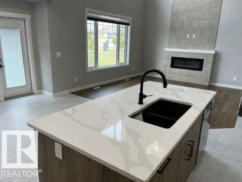 Kitchen island featuring a white countertop with grey veining, black undermount sink, and matte black faucet - 3810 46 Avenue, Beaumont, AB 
