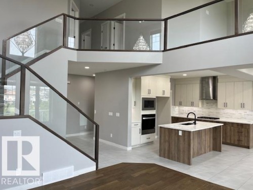 Open-concept living space featuring a modern kitchen with a large island and stainless steel appliances - 3810 46 Avenue, Beaumont, AB 