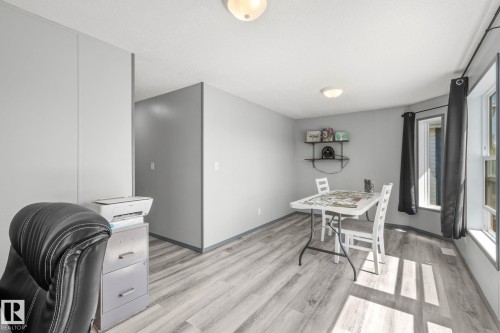 Spacious room featuring light grey walls, wood-finish flooring, two large windows, and a built-in wall shelf - 31 Graywood Cove, Stony Plain, AB 