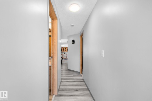 Hallway with light gray walls, wood-finish flooring, recessed ceiling lighting, and natural wood door frames - 31 Graywood Cove, Stony Plain, AB 