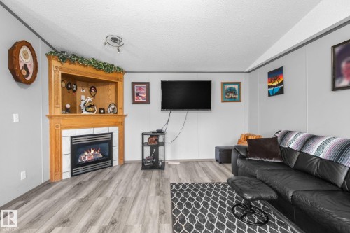 Entertainment space featuring a built-in fireplace with a light wood mantel and white tile surround - 31 Graywood Cove, Stony Plain, AB 
