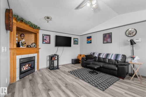 Corner fireplace with a wood surround and tiled hearth, complemented by wood-finish flooring - 31 Graywood Cove, Stony Plain, AB 