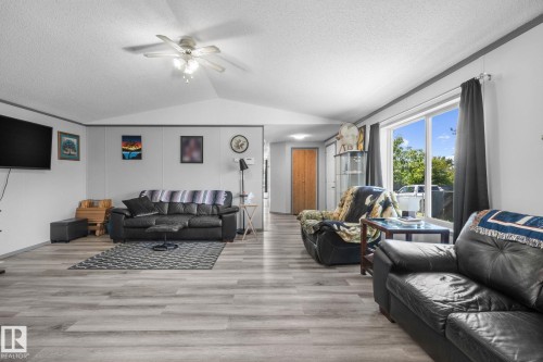 Bright living area featuring wood-finish flooring, a vaulted ceiling, and a ceiling fan with integrated lighting - 31 Graywood Cove, Stony Plain, AB 