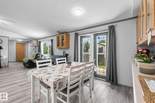Dining area featuring light wood-finish flooring, light gray walls, and French doors with privacy blinds - 31 Graywood Cove, Stony Plain, AB 