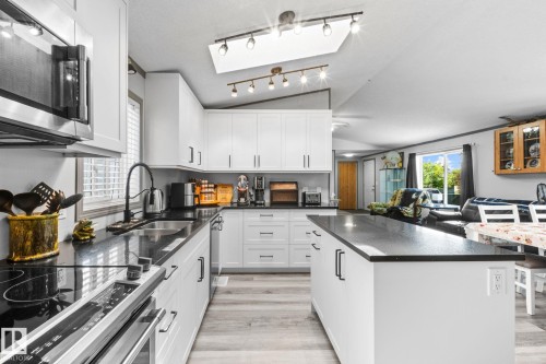 Modern kitchen featuring white cabinetry, dark countertops, and wood-finish flooring - 31 Graywood Cove, Stony Plain, AB 