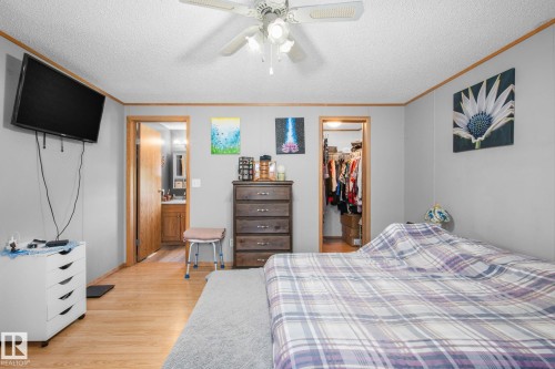 Bedroom space featuring wood-finish flooring, a ceiling fan with integrated lighting, and light gray wall paneling - 31 Graywood Cove, Stony Plain, AB 