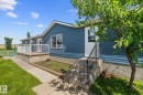 Exterior featuring blue siding, a deck with white railings, a concrete patio, and a mature tree - 31 Graywood Cove, Stony Plain, AB 