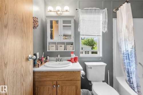 Bathroom featuring a light wood-finish vanity with a white countertop and oval sink, a wall-mounted mirrored medicine cabinet, and a toilet - 31 Graywood Cove, Stony Plain, AB 