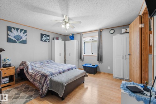 Spacious room featuring wood-finish flooring, a ceiling fan with integrated lighting, and a single window with curtain rods - 31 Graywood Cove, Stony Plain, AB 