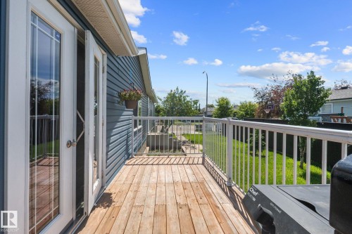 Spacious wood deck with white metal railing, offering direct outdoor access through double French doors - 31 Graywood Cove, Stony Plain, AB 