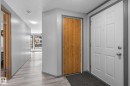 Entryway featuring a paneled door with polished hardware, wood-finish bi-fold closet doors, light wood-finish flooring, and grey trim - 31 Graywood Cove, Stony Plain, AB 