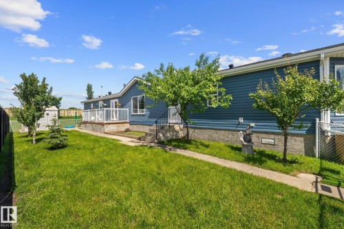 Expansive side yard featuring a manicured lawn, established trees, and a concrete pathway - 31 Graywood Cove, Stony Plain, AB 