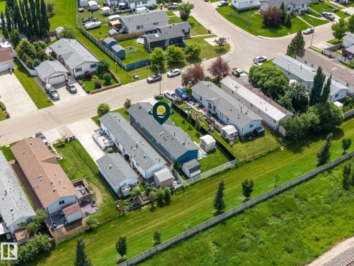 Aerial perspective featuring several residential properties with pitched roofs, surrounded by manicured lawns and mature trees - 31 Graywood Cove, Stony Plain, AB 