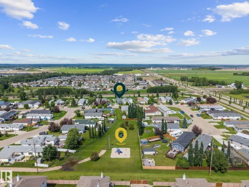 Aerial perspective showcasing a residential area with varied housing structures, green spaces, and a playground - 31 Graywood Cove, Stony Plain, AB 
