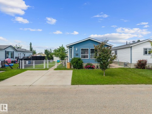 Blue siding exterior with white trim, featuring a manicured lawn and a concrete driveway - 31 Graywood Cove, Stony Plain, AB 