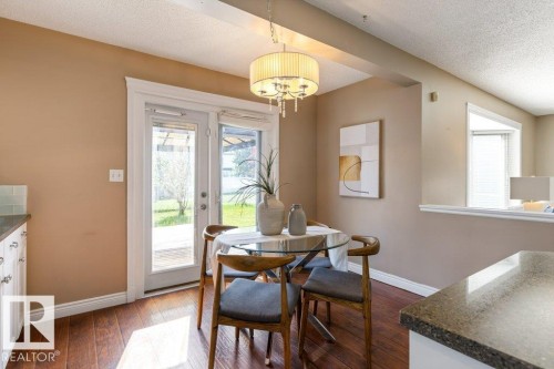 Dining area featuring wood-finish flooring, a contemporary chandelier, and direct access to the outdoors through double glass-paneled doors - 1119 Potter Greens, Edmonton, AB - Indoor Photo Showing Dining Room