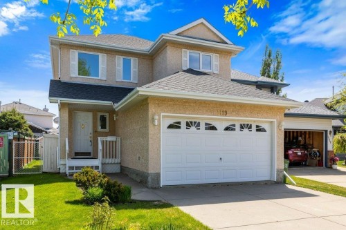 Two-story stucco exterior featuring a prominent attached two-car garage, front entry porch, and a well-maintained lawn - 1119 Potter Greens, Edmonton, AB - Outdoor With Facade