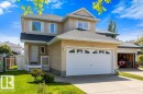 Two-story stucco exterior featuring a prominent attached two-car garage, front entry porch, and a well-maintained lawn - 1119 Potter Greens, Edmonton, AB  - Outdoor With Facade 