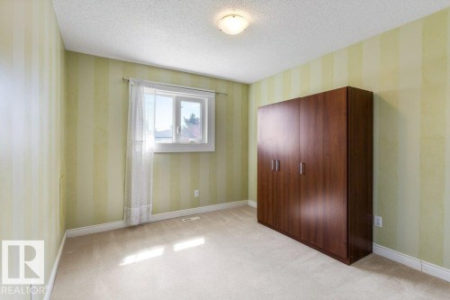 Neutral-toned carpet flooring and striped wall treatment define this room - 1119 Potter Greens, Edmonton, AB - Indoor Photo Showing Other Room