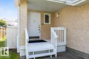 Covered front entry featuring a white panel door with brass hardware, stucco exterior, and white wood-finish stairs with railings - 1119 Potter Greens, Edmonton, AB  - Outdoor With Exterior 