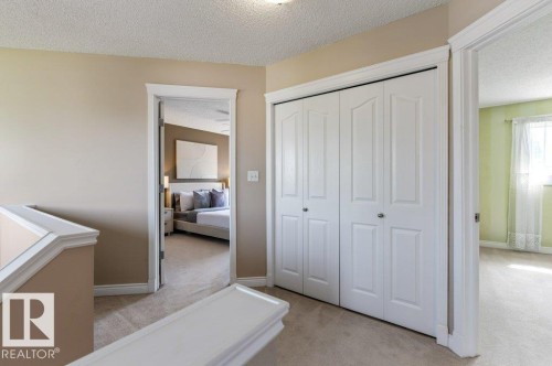 Hallway featuring neutral carpet flooring, white trim, and a bi-fold closet with white paneled doors - 1119 Potter Greens, Edmonton, AB - Indoor