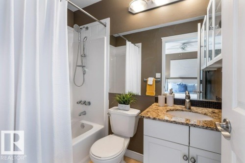 Full bathroom featuring a shower-tub combination with a wall-mounted shower head, a single-sink vanity with a granite countertop, and white cabinetry - 1119 Potter Greens, Edmonton, AB - Indoor Photo Showing Bathroom