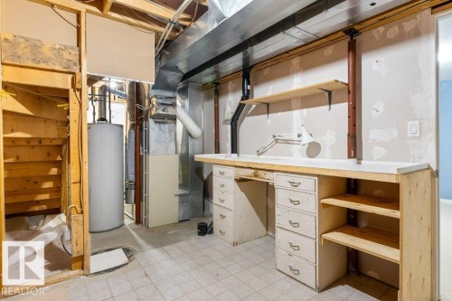 Utility area featuring a built-in workbench with drawers, overhead shelving, exposed ceiling joists, and a water heater - 1119 Potter Greens, Edmonton, AB - Indoor Photo Showing Basement