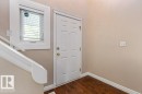Entryway featuring wood-finish flooring, a paneled door with brass hardware, and a window with blinds - 1119 Potter Greens, Edmonton, AB  - Indoor Photo Showing Other Room 