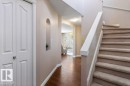 Inviting entryway featuring wood-finish flooring, a carpeted staircase with white railings, a decorative wall niche, and white bi-fold doors - 1119 Potter Greens, Edmonton, AB  - Indoor Photo Showing Other Room 