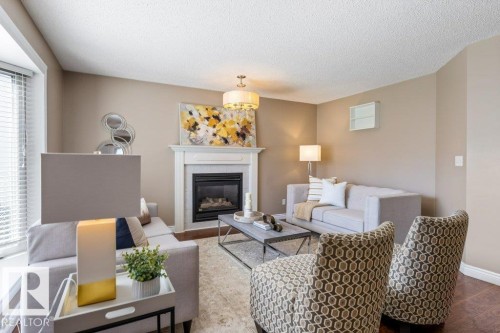 Living area featuring a white mantel fireplace with a dark insert, illuminated by an overhead chandelier - 1119 Potter Greens, Edmonton, AB - Indoor Photo Showing Living Room With Fireplace