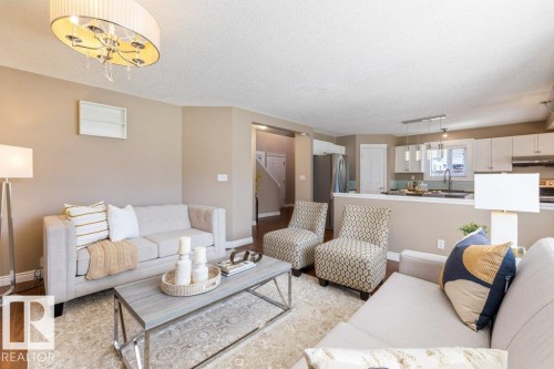 Open-concept living space featuring wood-finish flooring, a contemporary chandelier, and recessed lighting - 1119 Potter Greens, Edmonton, AB - Indoor Photo Showing Living Room