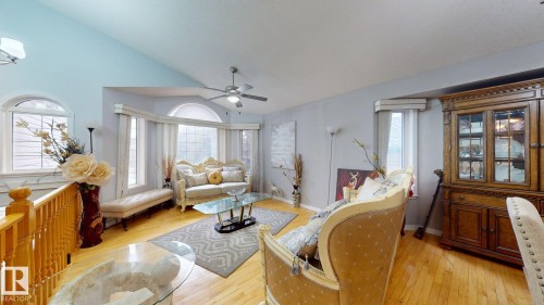 Bright living area featuring wood-finish flooring, a vaulted ceiling, and multiple arched windows - 3738 28A Street, Edmonton, AB 