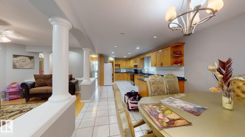 Open-concept interior featuring light wood-finish flooring, white tile flooring, and architectural columns - 3738 28A Street, Edmonton, AB 