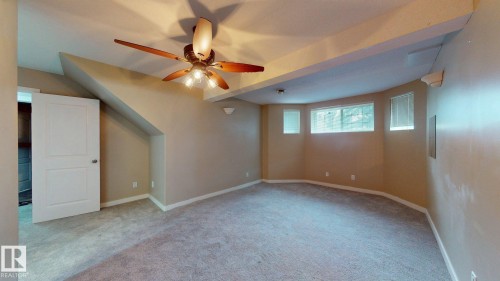Spacious room featuring neutral carpeting, a ceiling fan with integrated lighting, and multiple windows with blinds - 3738 28A Street, Edmonton, AB 