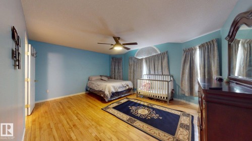 Expansive room featuring wood-finish flooring, a ceiling fan with integrated lighting, and multiple windows with drapery - 3738 28A Street, Edmonton, AB 