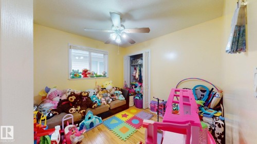 Room featuring wood-finish flooring, a window with exterior visibility, and a ceiling fan with light fixture - 3738 28A Street, Edmonton, AB 