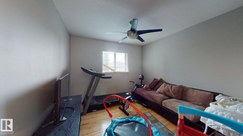 Room featuring wood-finish flooring, a ceiling fan with integrated lighting, and a window providing natural light - 3738 28A Street, Edmonton, AB 